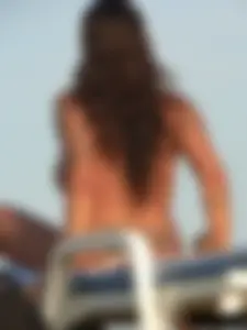 Topless tattooed lady on the beach with fake big tits