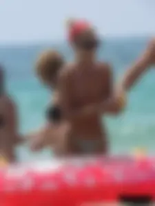 Topless skinny blonde lady in a g-string bikini at the beach