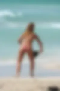 Topless girl in a tiny thong on the beach playing paddle ball