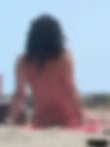 Brunette lady topless and in a black thong on the beach