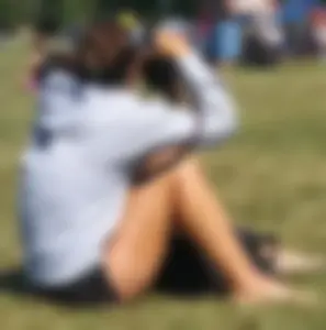 Candid Photographer Girl in Shorts and Sandals Sitting on the Grass in a Park