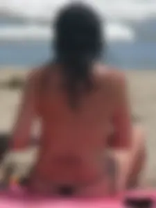 Brunette lady topless and in a black thong on the beach