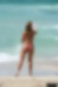 Topless girl in a tiny thong on the beach playing paddle ball