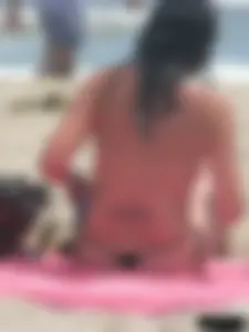 Brunette lady topless and in a black thong on the beach