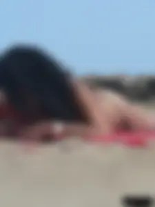 Brunette lady topless and in a black thong on the beach