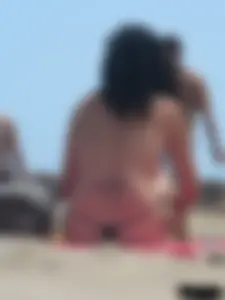 Brunette lady topless and in a black thong on the beach