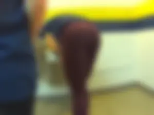 Skinny college teen in leggings bending over a drinking fountain
