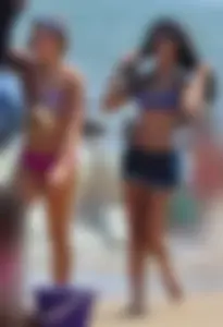 Hot beach brunette in shorts and bikini top with her friend in bikini