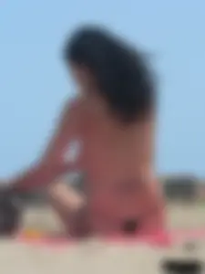 Brunette lady topless and in a black thong on the beach