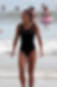 Skinny sexy lady on the beach in a black swimsuit