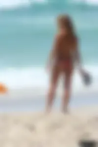 Topless girl in a tiny thong on the beach playing paddle ball