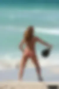 Topless girl in a tiny thong on the beach playing paddle ball