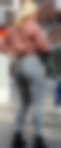 Blond girl in tight grey jeans waiting for the bus