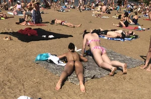 Gorgeous milf rubbing sun lotion in her skin at the beach, with a couple of her milf friends