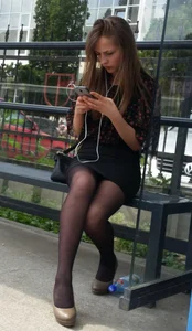 Girl in Dark Pantyhose and a Skirt Sitting on the Bus Stop Candid
