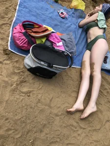 Cute Candid Girl in a Green Swimsuit With Pale Skin Lying on the Beach