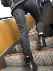 Legs in tight jeans closeup on subway escalator