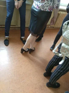 Closeups of a college girl's ass and legs and feet in high-heeled shoes: standing in a hallway and sitting at her desk in classroom