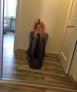 Selfie of a Teen Girl Sitting on the Floor with Thin Legs Dressed in Black Pantyhose