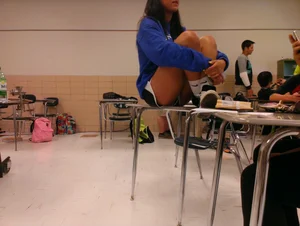 Cute Teen in Mini-Shorts Sitting on Top of a Desk in Classroom