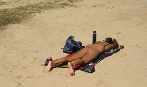 Sexy girl getting some sun laying on the beach in thong bikini