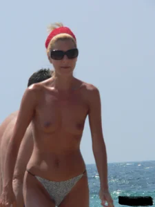 Topless skinny blonde lady in a g-string bikini at the beach