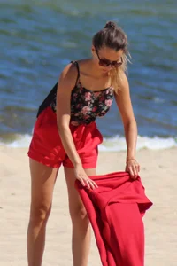 Hottie undressing from her red shorts to her bikini to layout on the beach