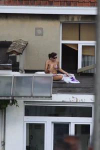 Neighbor on rooftop tanning in bikinis