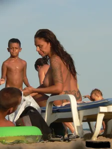 Topless tattooed lady on the beach with fake big tits