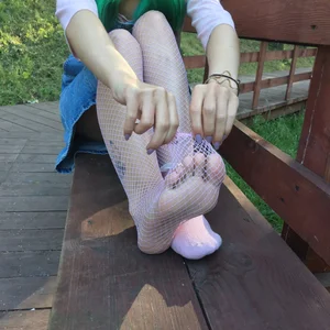 Feet in Fishnet Pantyhose Closeup on the Park Bench