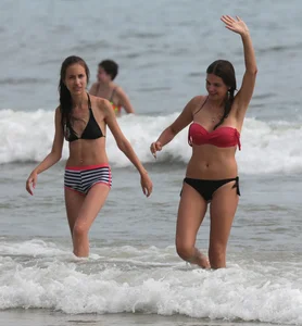 Skinny small boobed girl in a bikini on the beach with her friend