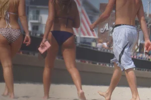 Two sexy friends, one blonde and one brunette, on the beach in bikinis