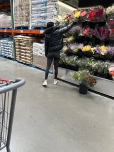 Girl in leggings with a perfect ass and slim legs picking flowers at the supermarket creepshots