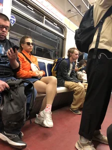 Subway Candid Girl in Denim Shorts and Sneakers Sitting With Crossed Legs in the Train