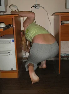 Barefoot teen in a top and grey pants bending over to pick up something on the floor
