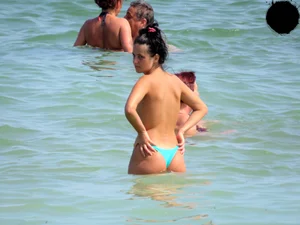 Brunette topless babe with cute tits and a nice ass in a thong bikini