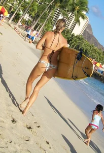 Skinny blonde surfer on the beach in little bikini