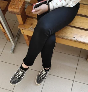 College Teen Girl Sitting With Crossed Legs, Dressed in Tight Black Pants