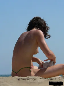 Topless beach milf looking sexy in a tiny g-string bikini