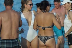 Girl in Sunglasses and a White One Piece Swimsuin Standing on Sand Beach Creepshots