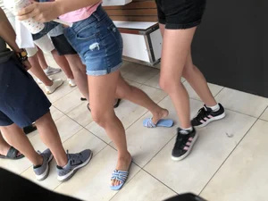 Two skinny teens in shorts at food court, nice skinny legs