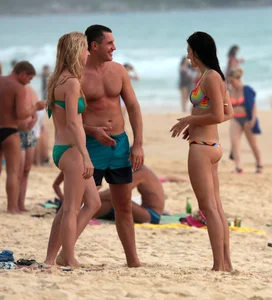 Sexy brunette in thong bikini and blonde friend in green bikini at the beach