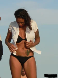 Topless tattooed lady on the beach with fake big tits