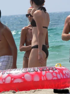 Topless skinny blonde lady in a g-string bikini at the beach
