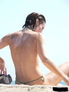 Topless beach milf looking sexy in a tiny g-string bikini