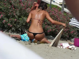 Sexy girl on the beach getting some sun in a little black thong bikini