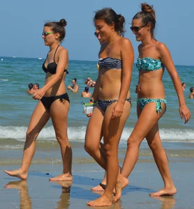 Foursome bikini friends walking the beach
