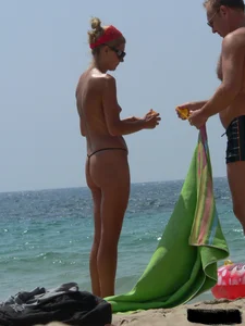 Topless skinny blonde lady in a g-string bikini at the beach