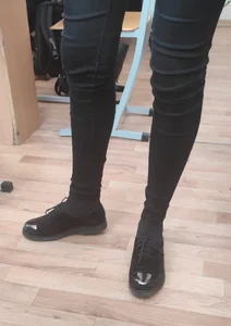 Slim Legs of a College Teen Girl in Tight Pants, Closeup Photo in Class