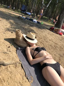 Girl in a Black Swimsuit Lying on a Beach With Her Face Covered With a Hat Creepshots